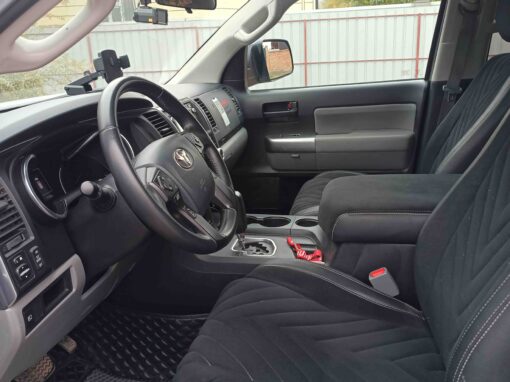 Intérieur d'un 4x4 au Kirghizistan, montrant le tableau de bord, le volant et les sièges baquets avant revêtus d'une sellerie noire texturée.