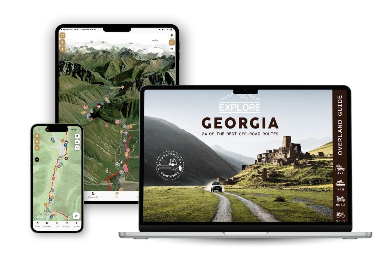 A smartphone, tablet and laptop display maps and a travel guide to explore Georgia's off-road trails, with mountainous terrain and a picturesque rural landscape with ruins.