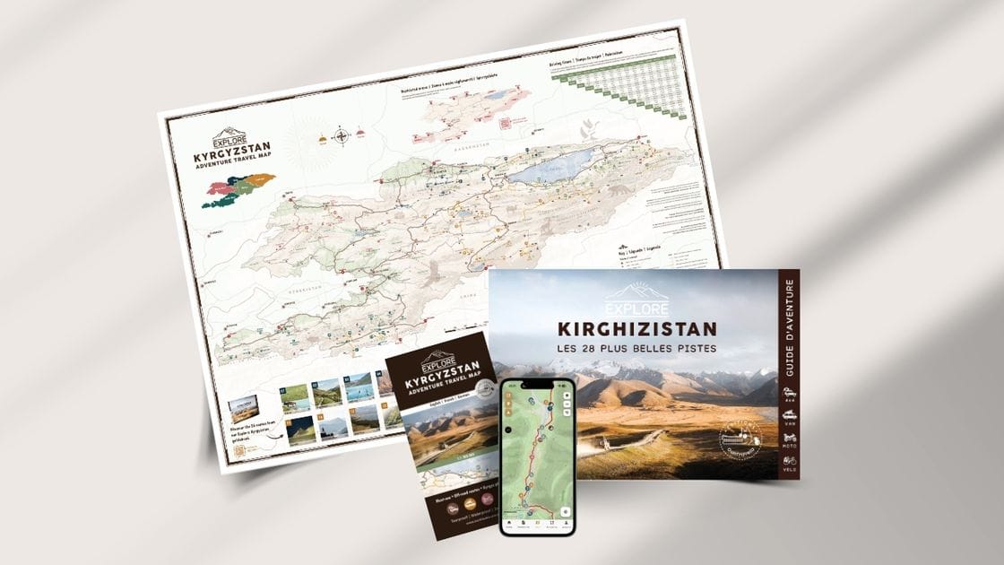 Une carte du Kirghizistan est affichée à côté d'un guide de voyage intitulé "Explore Kirghizistan : Les 28 Plus Belles Pistes", d'une brochure pliée et d'un smartphone affichant une carte numérique, le tout sur un fond clair.