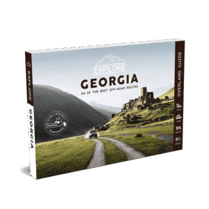 Explore Namibia Travel Guide 51 The Explore Georgia Travel Guide features a panoramic image of a car heading towards ancient stone ruins in green hills, with majestic mountains in the background.