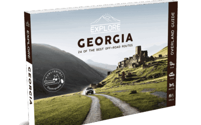 The Explore Georgia Travel Guide features a panoramic image of a car heading towards ancient stone ruins in green hills, with majestic mountains in the background.