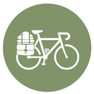 Icône représentant un vélo blanc muni de sacoches à l'arrière, sur fond circulaire vert.