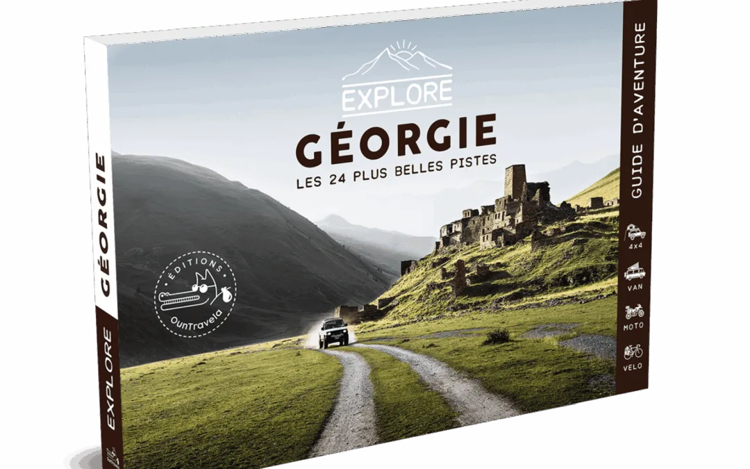 Le Guide de voyage Explore Géorgie présente une image panoramique d'une voiture se dirigeant vers d'anciennes ruines en pierre dans des collines verdoyantes, avec des montagnes majestueuses à l'arrière-plan.